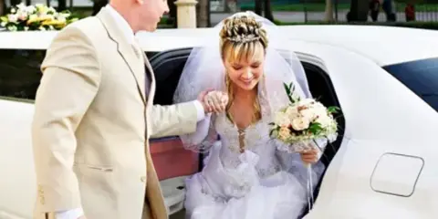 Bride and groom exiting a white limousine during a wedding