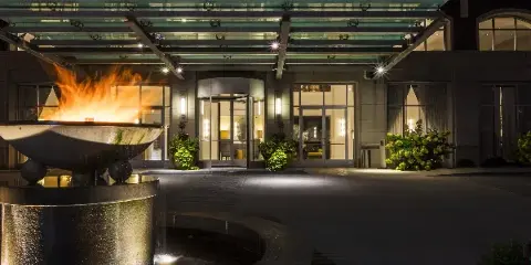 Nighttime exterior view of the Hotel Blackhawk entrance with a fire bowl and glass canopy.