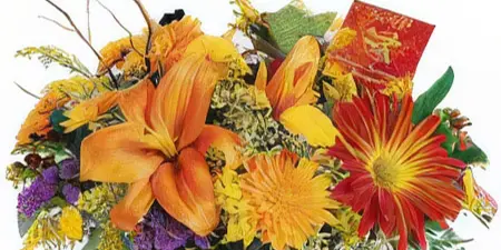 A floral arrangement featuring orange lilies, red daisies, and yellow chrysanthemums in a red glass vase.
