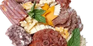 A large, vertically arranged catering platter featuring an assortment of cured meats, cheeses, and garnishes.