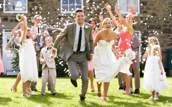 A bride and groom dancing at a wedding reception while guests throw flower petals.