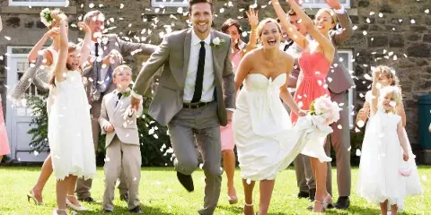 A bride and groom dancing at a wedding reception while guests throw flower petals.