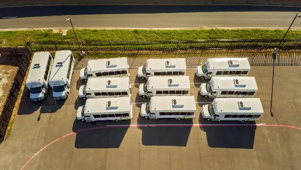 Aerial view of a fleet of white GoBus transit buses parked in a lot.