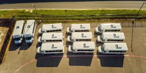 Aerial view of a fleet of white GoBus transit buses parked in a lot.