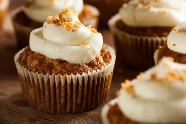 A close-up photograph of a cupcake with white frosting and crumb topping in a paper liner.