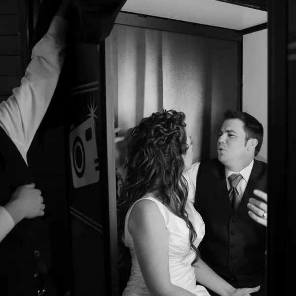 A bride and groom posing together inside a photo booth.