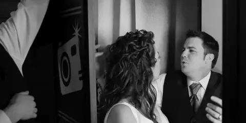 A bride and groom posing together inside a photo booth.