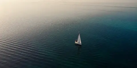 Aerial view of a sailboat on calm, turquoise water in the Florida Keys.