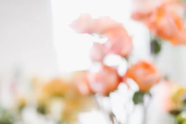 A close-up photograph of a bouquet of peach and orange roses with green stems.