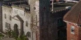 Aerial view of the historic Castle & Key distillery complex featuring stone buildings, a copper water tower, and surrounding wooded grounds.