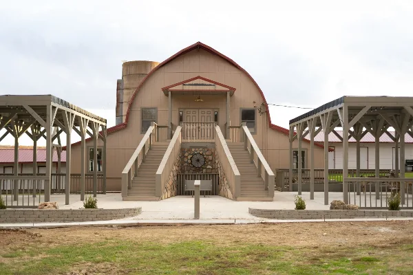 Exterior view of a large building with an arched roof and outdoor covered pavilions.