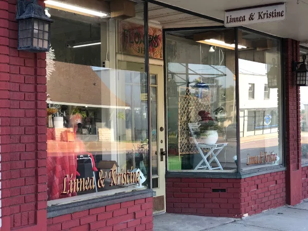 Exterior view of the Linnea & Kristine florist storefront with red brick walls and large display windows.