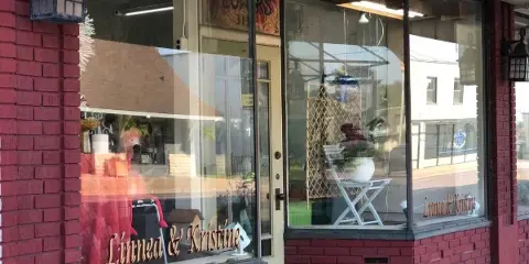 Exterior view of the Linnea & Kristine florist storefront with red brick walls and large display windows.