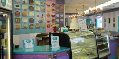 Interior of Sweet Stuff Bakery showing display cases of baked goods and a wedding cake.