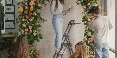 Floral designers assembling a large, custom floral arch in a studio.