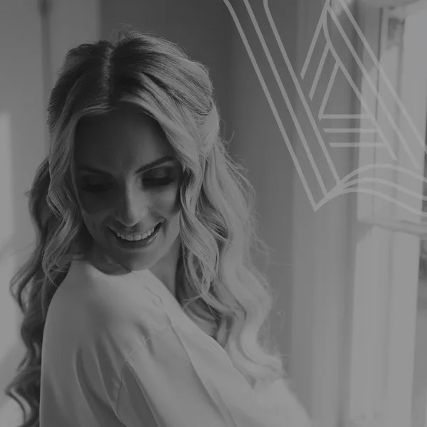 Black and white portrait of a smiling bride with styled wavy hair and makeup