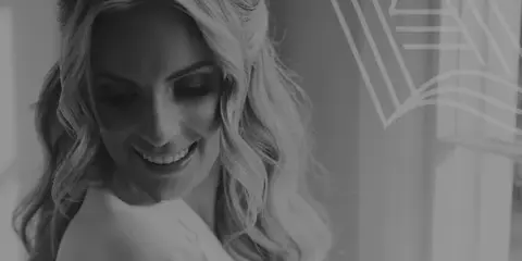Black and white portrait of a smiling bride with styled wavy hair and makeup