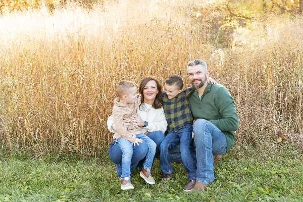 A family of four posing together in a field of tall golden grass.