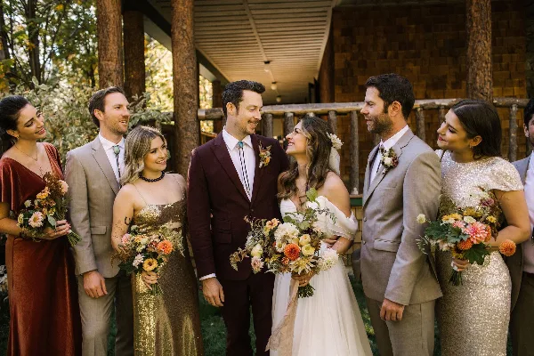 A wedding party including the bride and groom holding colorful, garden-inspired floral bouquets and boutonnieres.