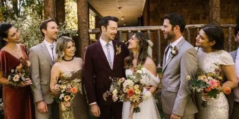 A wedding party including the bride and groom holding colorful, garden-inspired floral bouquets and boutonnieres.