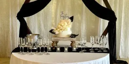 A wedding event setup featuring a sweetheart table with a white tablecloth, champagne flutes, and a decorative backdrop with a skull, horns, and dried florals.
