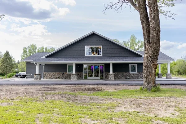 Exterior view of the Hidden River Acres Event Center building with dark siding and stone foundation.