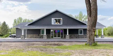 Exterior view of the Hidden River Acres Event Center building with dark siding and stone foundation.