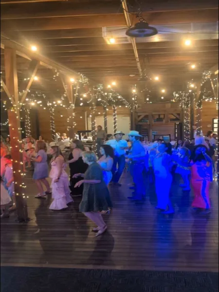 Packed wedding dance floor with guests dancing under string lights