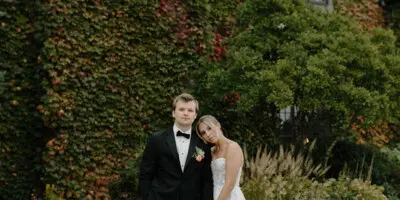 A bride and groom standing together in front of an ivy-covered building.