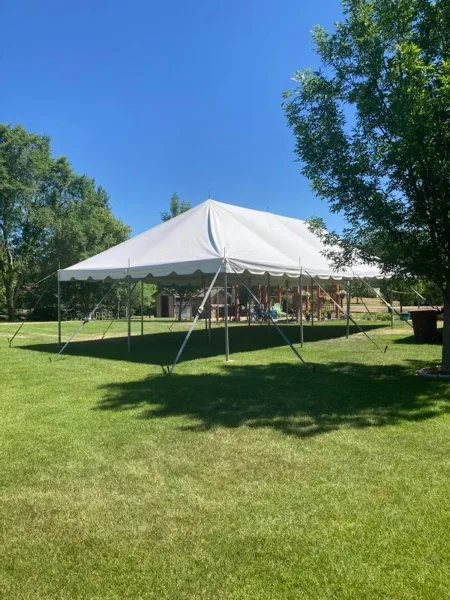 A large white event tent set up on a grassy lawn under a clear blue sky.