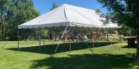 A large white event tent set up on a grassy lawn under a clear blue sky.