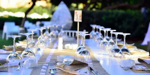 A close-up view of a decorated event table featuring a burlap runner, white linens, and inverted wine glasses.