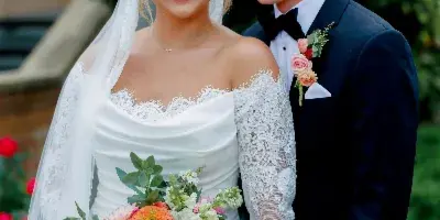 A bride and groom posing together, with the bride holding a colorful, garden-inspired wedding bouquet.