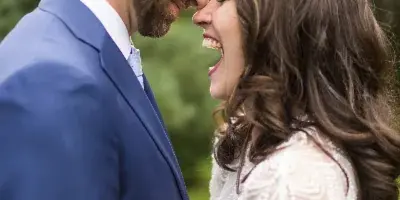 A bride and groom smiling at each other outdoors in a field.