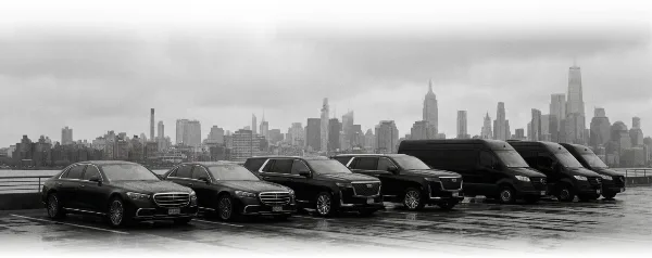 A lineup of luxury black sedans, SUVs, and vans parked in front of the New York City skyline.