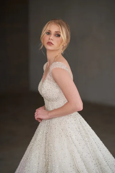 Bride in a beaded wedding gown with styled hair and makeup