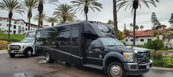 A black MIB Transportation 28-passenger shuttle bus parked outdoors with palm trees in the background.