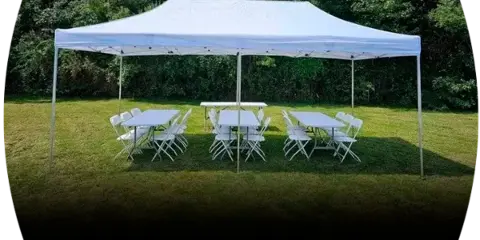 White canopy tent set up on a grassy lawn with rectangular tables and white folding chairs arranged underneath.
