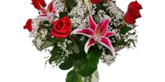 A floral arrangement featuring red roses and pink lilies in a clear glass vase.
