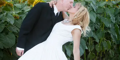 A bride and groom kissing in a field of sunflowers.