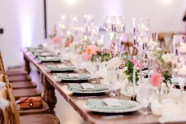 A long reception table styled with pink florals and elegant place settings at Hyla Brook Estate.