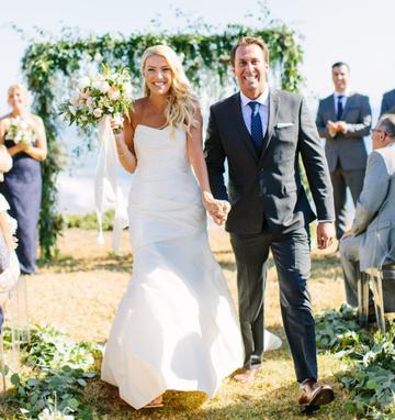 A bride and groom walking down the aisle at an outdoor wedding ceremony.