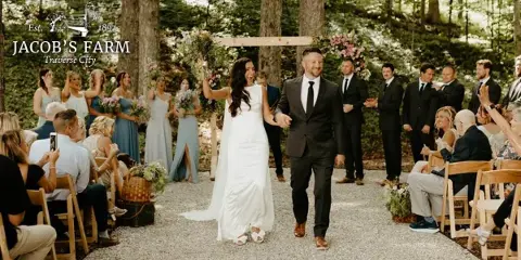 A bride and groom walking down a gravel aisle during an outdoor wedding ceremony at a farm venue.