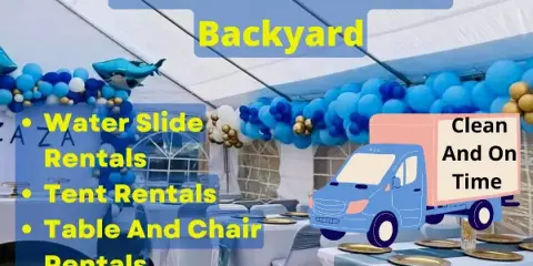 A white event tent set up outdoors with tables, chairs, and blue and gold balloon decorations.
