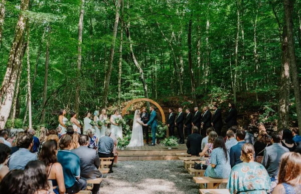 Outdoor wedding ceremony in a forest with a wooden arch and stage