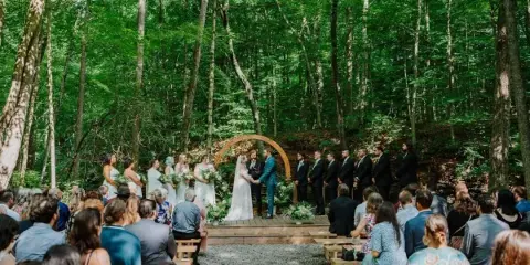 Outdoor wedding ceremony in a forest with a wooden arch and stage