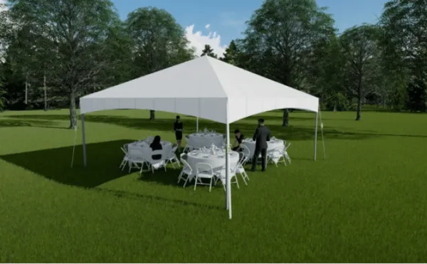 A white event tent set up on a grassy field with white tables and chairs arranged underneath.