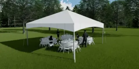 A white event tent set up on a grassy field with white tables and chairs arranged underneath.