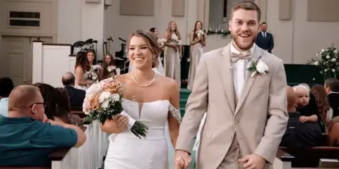 A bride and groom walking down a church aisle during a wedding ceremony.