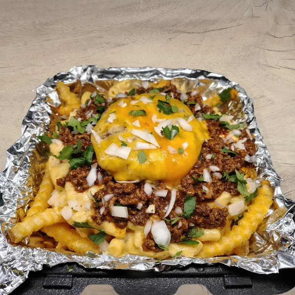 A catering plate featuring crispy fries, mac and cheese, meat sauce, and a cheeseburger served in a foil-lined container.